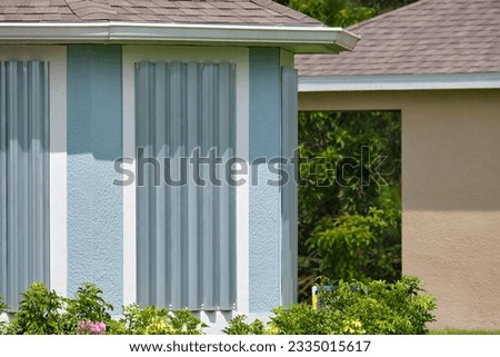 Steel sheets mounted as storm shutters for hurricane protection of house windows. Protective measures before natural disaster in Florida Royalty-Free Stock Photo #2335015617