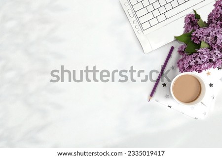 Computer,lilac flowers and a cup of coffee on a light table.Desktop of a modern woman, home office. Minimal business concept, home comfort and lifestyle, template for design, flat lay, space for text.