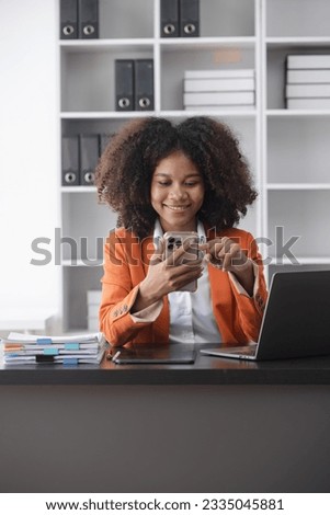 Young African American businesswoman working with smartphone at desk in office, business finance technology concept.