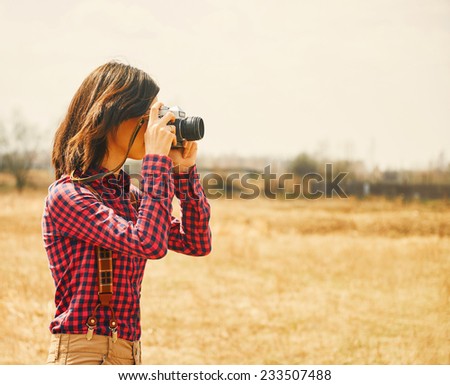 Young woman takes photographs with vintage photo camera in autumn outdoor