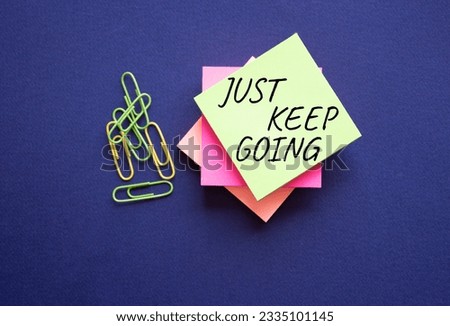 Just keep going symbol. Yellow steaky note with paper clips with words Just keep going. Beautiful deep blue background. Business and Just keep going concept. Copy space.