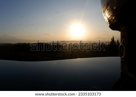 photo of a swimming pool with a very beautiful and luxurious design, located on a mountain, with a view of the sunrise. extraordinary views