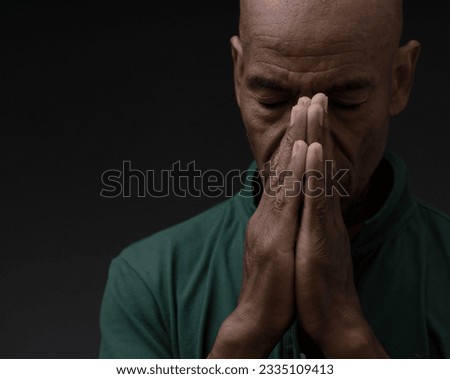 man praying to god with hands together Caribbean man praying with people stock photo	