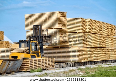 Forklift loading lumber wood boards in stack, finished product warehouse ready for transportation. Sawn boards stack in row. Worker on loader stack in row wooden boards at sawmill Royalty-Free Stock Photo #2335118801