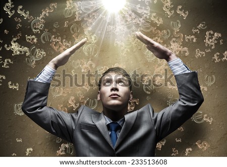 Businessman protecting head with arms from falling currency signs