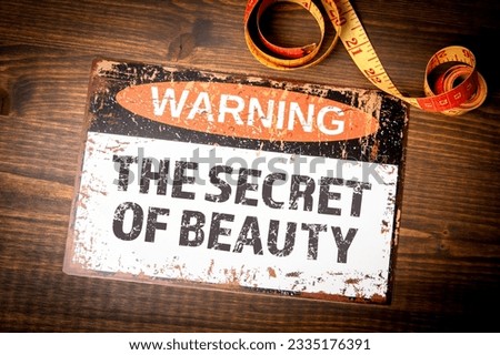 The secret of beauty. Warning sign on wood texture background.
