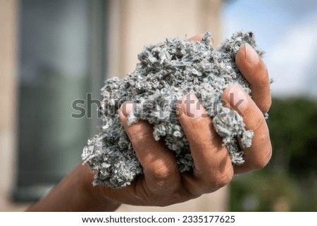 Cellulose insulation for walls and floors In hand. Recycled newsprint. Heat preservation and energy saving. Royalty-Free Stock Photo #2335177625