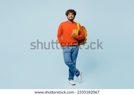 Full body young happy fun cheerful teen Indian boy student he wearing casual clothes backpack bag hold books isolated on plain pastel light blue cyan background. High school university college concept Royalty-Free Stock Photo #2335182067