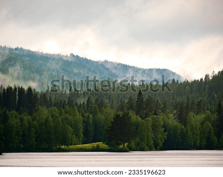 Misty forested mountains over the Lake Tvallen. It is situated east of Axland, southwest of Tastorp. Idyllic Swedish landscape. Sweden. Northern Europe. Royalty-Free Stock Photo #2335196623