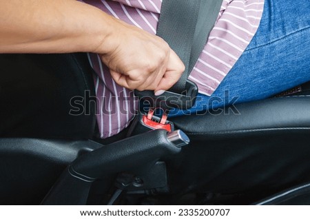 hand of an elderly woman fastening seat belt in car, close up. concept of safe travel Royalty-Free Stock Photo #2335200707