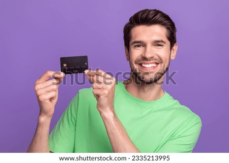 Photo of cheerful friendly nice man with stubble green t-shirt hands demonstrate debit plastic card isolated on purple color background