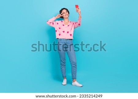 Full size length body photo of young friendly woman blogger make video recording show v sign peace selfie isolated on blue color background