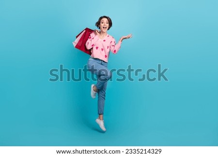 Full body photo of crazy funky woman jumping positive holding red packages bargains shopaholic brand sale isolated on blue color background