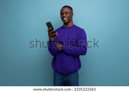 handsome young african guy in blue sweatshirt is using phone