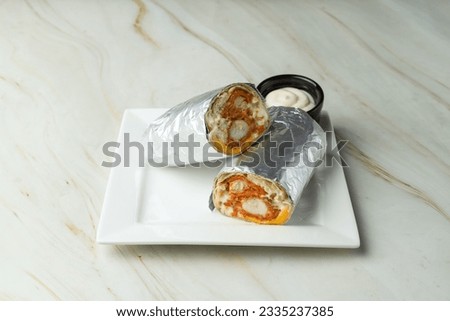Chicken fajita wrap sandwich or burrito with dip on white background.