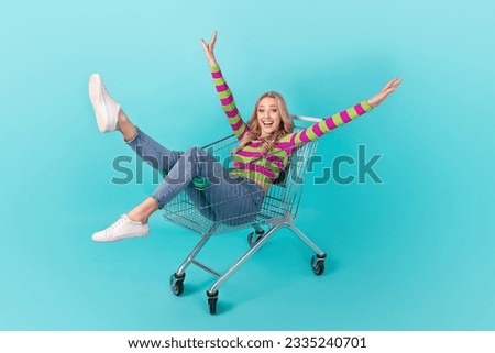 Full length photo of adorable excited lady wear striped pullover riding supermarket tray isolated teal color background