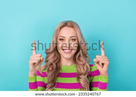 Photo portrait of pretty young girl toothy smile promotion point up wear trendy striped outfit isolated on cyan color background