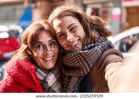 Two women mother and daughter make selfie by camera at street