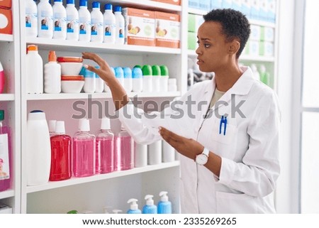 African american woman pharmacist holding bottle reading prescription at pharmacy