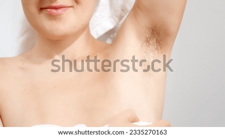 Closeup of young woman covered in white towel showing her long dark armpit hair. Concept of beautiful female, natural beauty, feminity and body hair