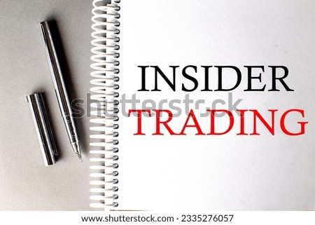 INSIDER TRADING text on notebook with pen on grey background