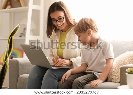 Nanny with little boy watching cartoons at home