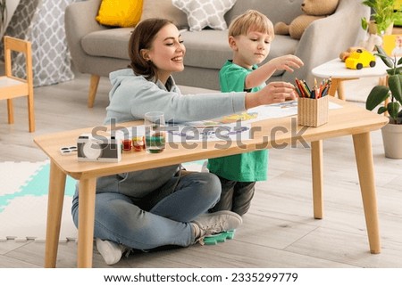 Nanny with little boy drawing at home Royalty-Free Stock Photo #2335299779