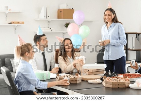 Young woman making toast at birthday party in office