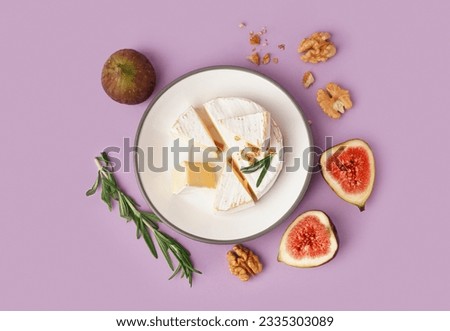 Plate with pieces of tasty Camembert cheese on lilac background Royalty-Free Stock Photo #2335303089