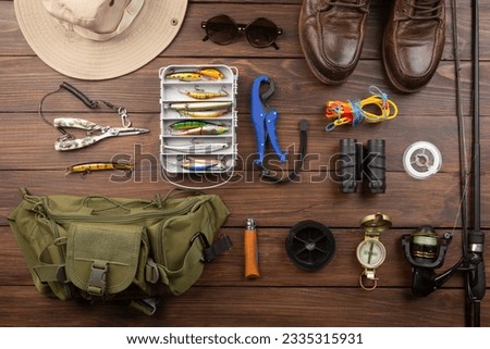 Fishing rod, tackles and other stuff for recreation activity on the desk. Fishing season concept Royalty-Free Stock Photo #2335315931