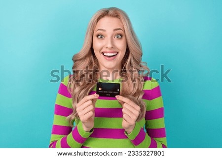 Photo of impressed astonished cute woman wavy hairstyle dressed striped sweatshirt hold plastic card isolated on teal color background
