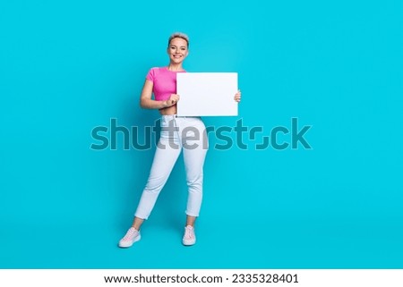 Full length photo of adorable lovely woman dressed pants sneakers falling hold white placard empty space isolated on blue color background Royalty-Free Stock Photo #2335328401