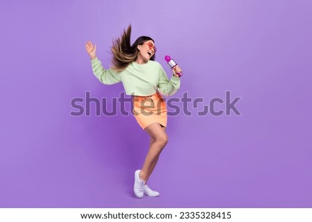 Portrait of good mood pleasant girl wear stylish pullover skirt holding microphone singing song isolated on violet color background Royalty-Free Stock Photo #2335328415