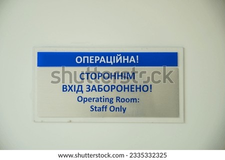room name plate on the wall in the corridor of the hospital. Translation: operating room. unauthorized entry is prohibited. High quality photo