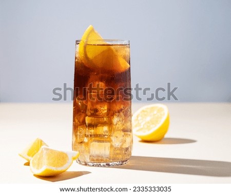 Iced tea with lemon and ice in a tall glass on a yellow background. The concept of a refreshing drink or lemonade on a hot summer day. Front view and copy space.