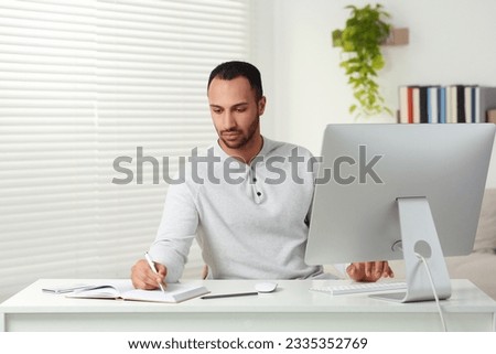 Young man working on computer at desk in room. Home office