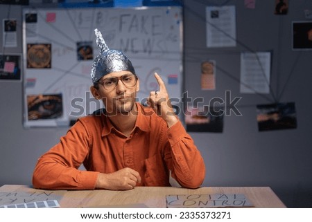 close-up of a male conspiracy theorist in a protective foil cap and glasses debunks myths. Conspiracy theory and the harm of the 5g network. Copy space Royalty-Free Stock Photo #2335373271