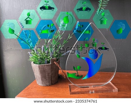A wooden pot and a clear acrylic frame designed with ECO, an environmental symbol. the green leaf is to preserve the forest, the  plant trees to make the world green.	