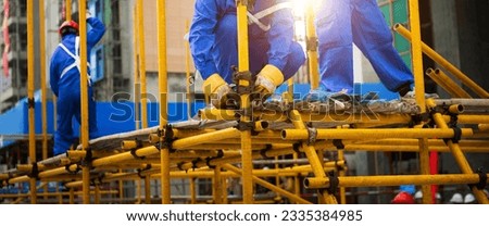 Construction workers working on scaffolding Royalty-Free Stock Photo #2335384985