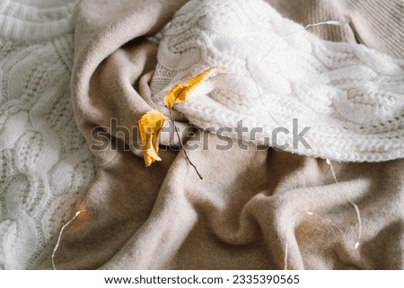 Background with warm sweaters. Pile of knitted clothes with autumn leaves, warm background, knitwear, space for text, Autumn winter concept. Copy Space.