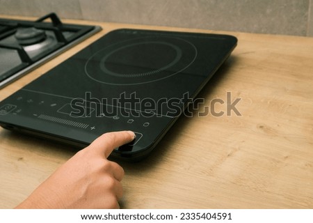 Woman hand turn on induction stove. Finger touching sensor button on induction or electrical hob. Induction cooktop. Switching on the burner cooktop. Royalty-Free Stock Photo #2335404591