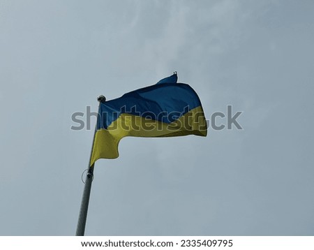 The national flag of Ukraine flutters in the wind in the clouds