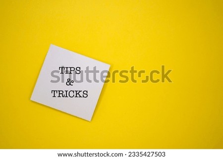 White sticky note with the word TIPS AND  TRICKS on yellow background