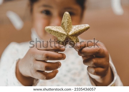 Happy and smiling girl holding Christmas decorative objects in her hands, such as Christmas balls and letters spelling 'Merry Christmas' in English. Christmas concept, love, peace.Selective focus