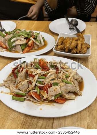 Papaya Salad is Thai food eaten with fried chicken wings and sticky rice.