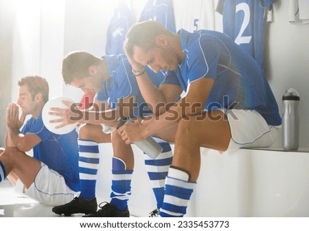 Disappointed soccer players sitting in locker room Royalty-Free Stock Photo #2335453773
