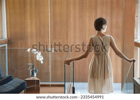 Woman standing at top of stairs in modern house Royalty-Free Stock Photo #2335454991