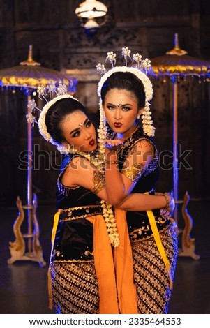 two Javanese dancers in yellow scarves taking pictures with ridiculous faces on stage