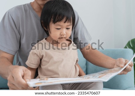 father relax and read book with baby time together at home. parent sit on sofa with daughter and reading a story. learn development, childcare, laughing, education, storytelling, practice.