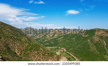 A panoramic view on Daqing mountains in Inner Mongolia. Endless mountain chains. The slopes are overgrown with small bushes and grass. Desolated landscape. Clear and sunny. Bio diversity of a region Royalty-Free Stock Photo #2335499385